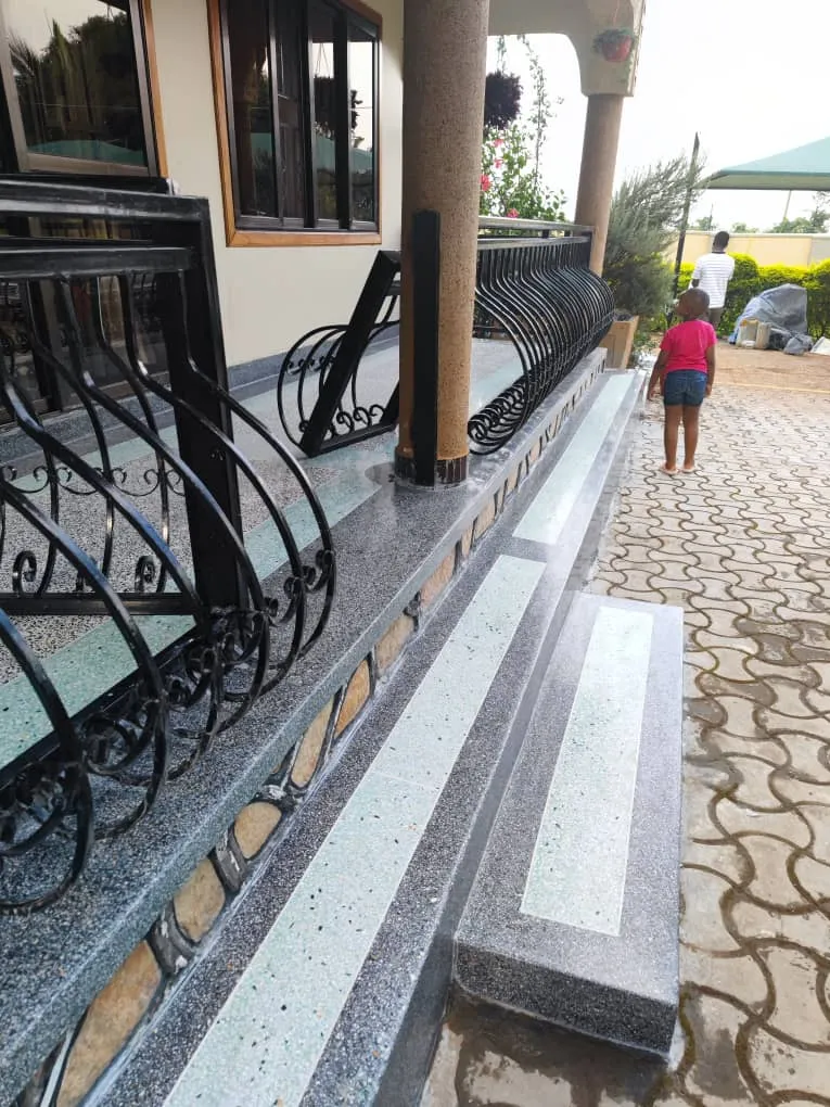 Terrazzo staircase with dark polished treads and an iron railing